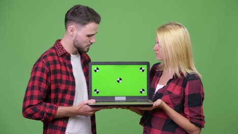 Young happy couple smiling while showing laptop together