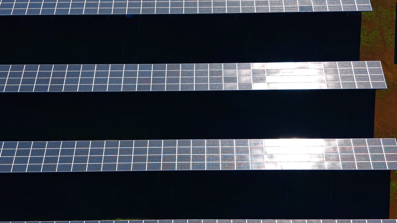 Vista dall'alto di pannelli fotovoltaici in un parco solare. Veduta zenitale diretta di pannelli solari disposti in file strutturate su una superficie di campo verde