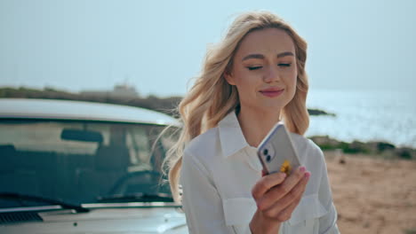 cute model holding telephone posing on summer beach closeup. blonde smartphone