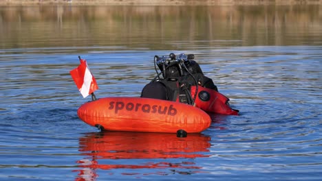 a diver prepares to dive into the water, he is with his red buoy