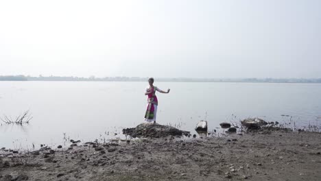 A-bharatnatyam-dancer-displaying-a-classical-bharatnatyam-pose-in-the-nature-of-Vadatalav-lake,-Pavagadh