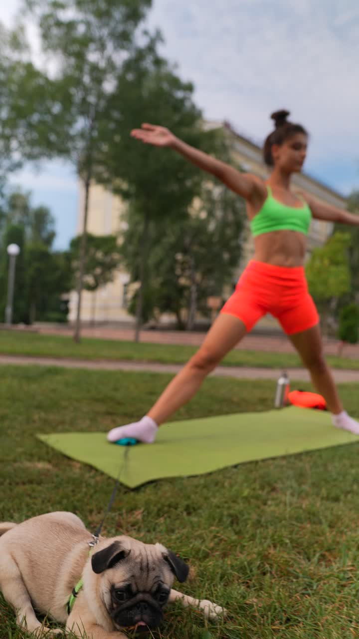 mujer practicando yoga en un parque con un cachorro