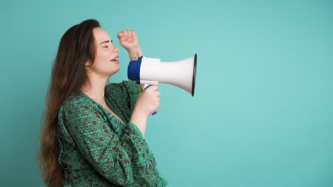 young woman protesting with megaphone in blue studio