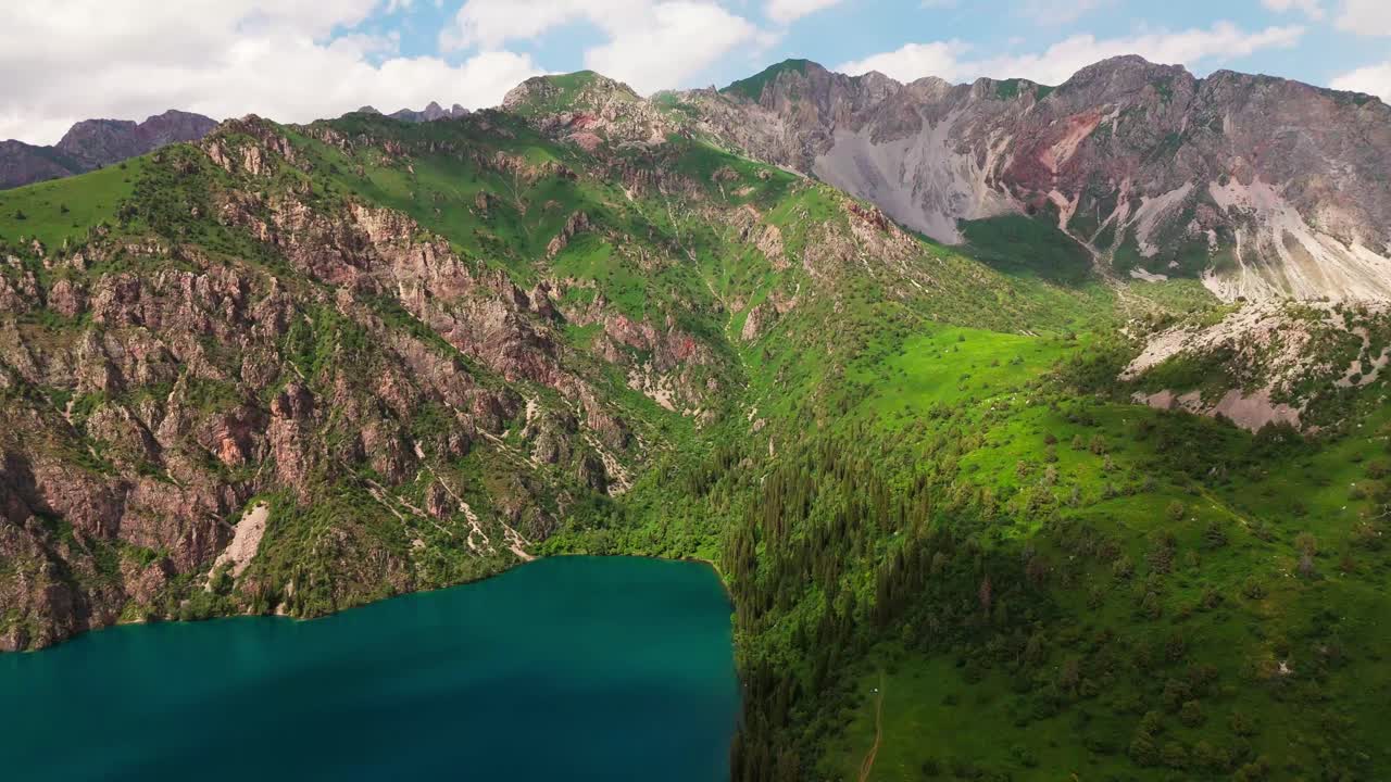 drone approaching rocky mountains and blue lake in sary chelek lake in Kyrgyzstan