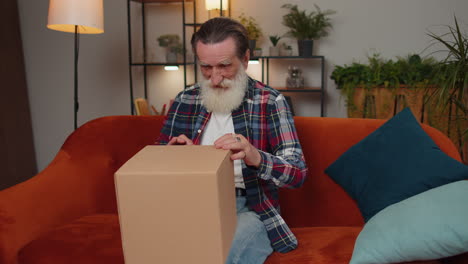 Happy-senior-man-shopper-unpacking-cardboard-box-delivery-parcel-online-shopping-purchase-at-home