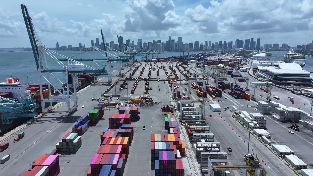 Aerial view of the port of Miami, Florida, showing colorful shipping containers and cranes, with overlay words highlighting economy, goods shipment, inflation, recession, risk and tariffs