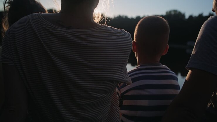 Video di famiglia che si rilassa in riva al lago durante il tramonto