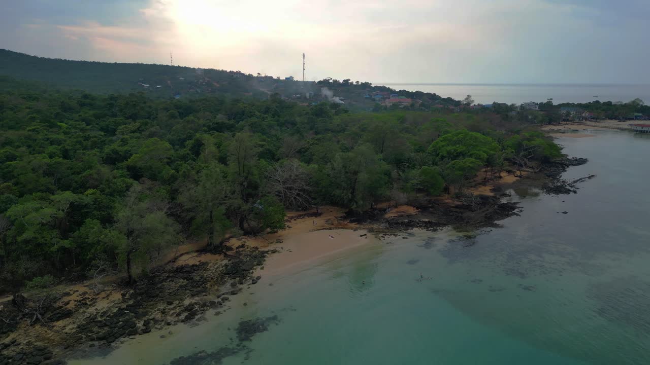 Koh Rong Sanloem island village in Cambodia, featuring turquoise water, pier, boats and tropical jungle. Unique aerial view flight wide orbit overview drone