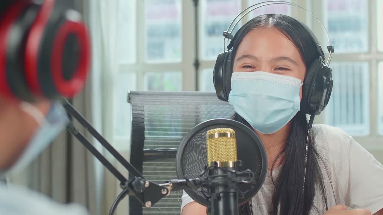 Over Shoulder View Of Boy Interview Kid Girl Guest Wearing Protect Mask And Headphone For Content In Podcast Studio. Content Creator Concept