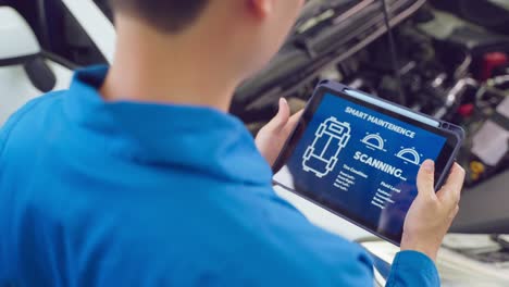 close up of automotive mechanic running diagnostics software on tablet. asian young vehicle service manager worker work in mechanics garage, check and maintenance to repair the engine car in workshop.