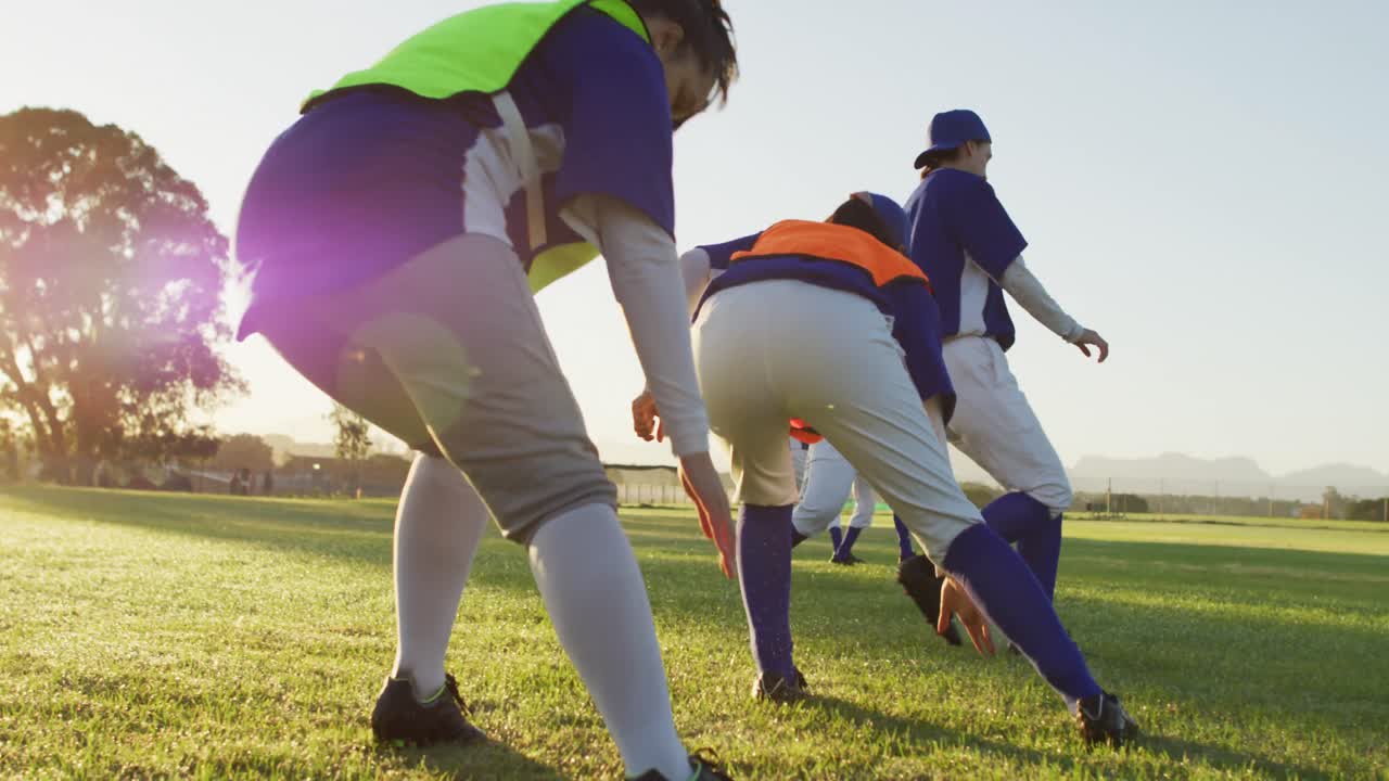 grupo diverso de jugadoras de béisbol ejercitándose en el campo, corriendo y tocando el suelo