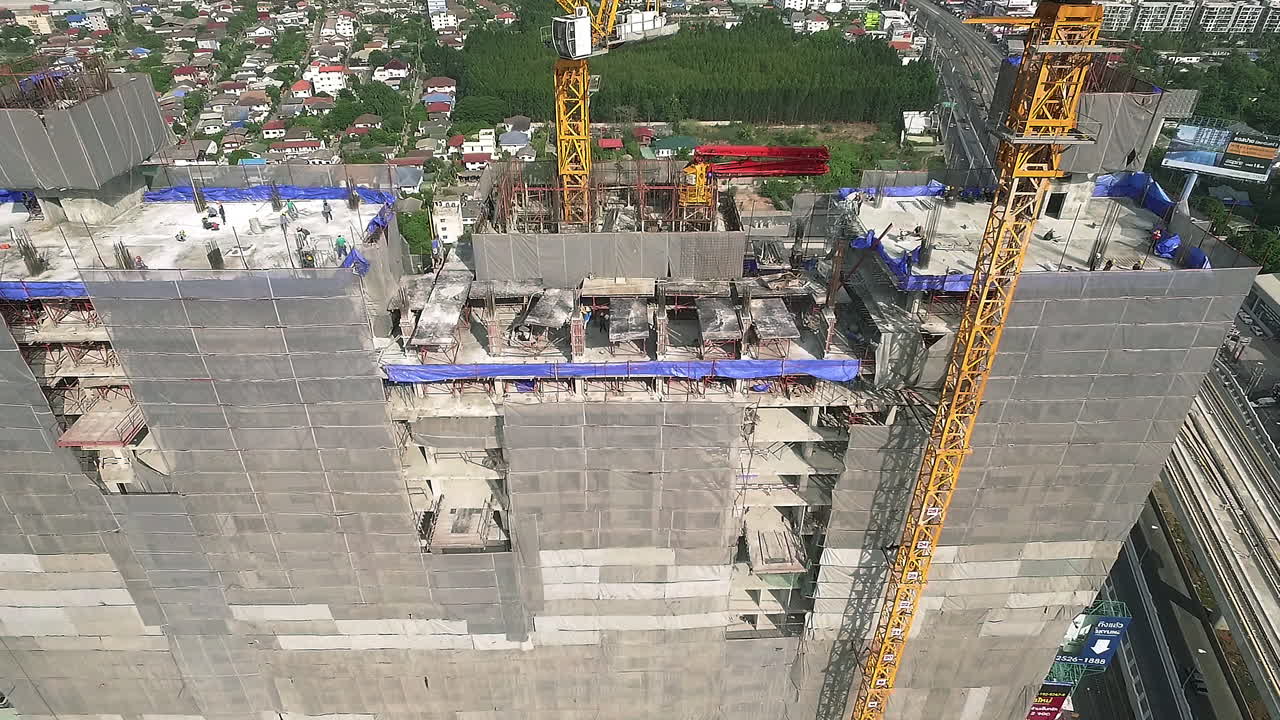 vista aérea de un moderno edificio de gran altura en construcción en el ajetreado distrito de negocios del centro de la ciudad con trabajadores, andamios y grúas