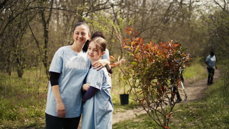 portrait of mother and daughter volunteering to clean up a forest area