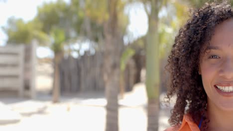 Portrait-of-happy-biracial-woman-looking-at-camera-at-beach-house