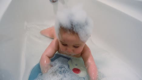 cute six months old baby boy having a bath on his tummy