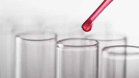 Video-of-glass-laboratory-test-tubes-and-pipette-with-red-liquid-and-copy-space-on-white-background