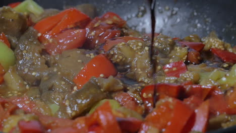 verter salsa de soja en la sartén con un plato vegetariano