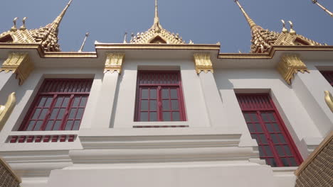 walking in and out  of the outside of a popular tourist attraction white and gold buddhist temple in the city of bangkok in thailand