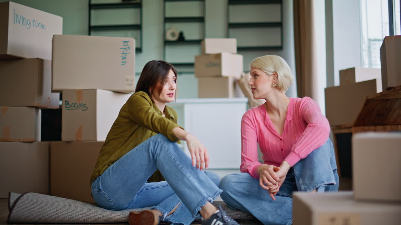 Property owners sitting floor discussing future interior around cardboard boxes