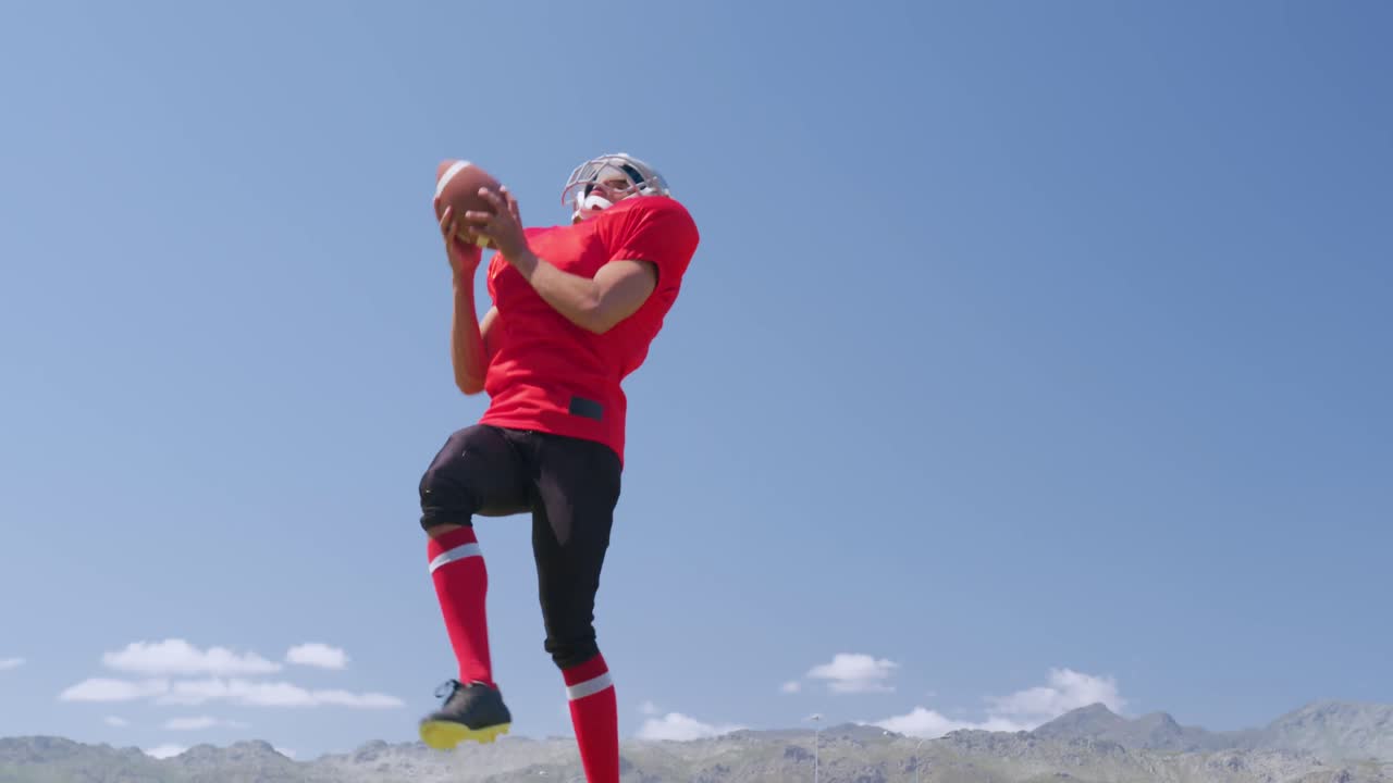 Giocatore di football americano che salta per prendere una palla