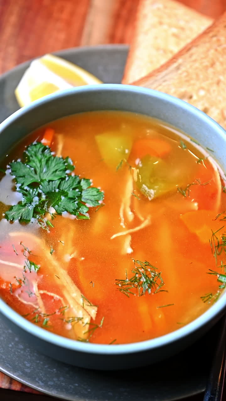 Bright chicken soup with vegetables and parsley. Clear chicken broth with vegetables and herbs served in bowl