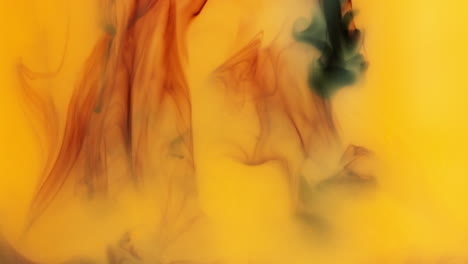 orange and black paint or dye dropped into water against white background to create swirling colourful smoke background