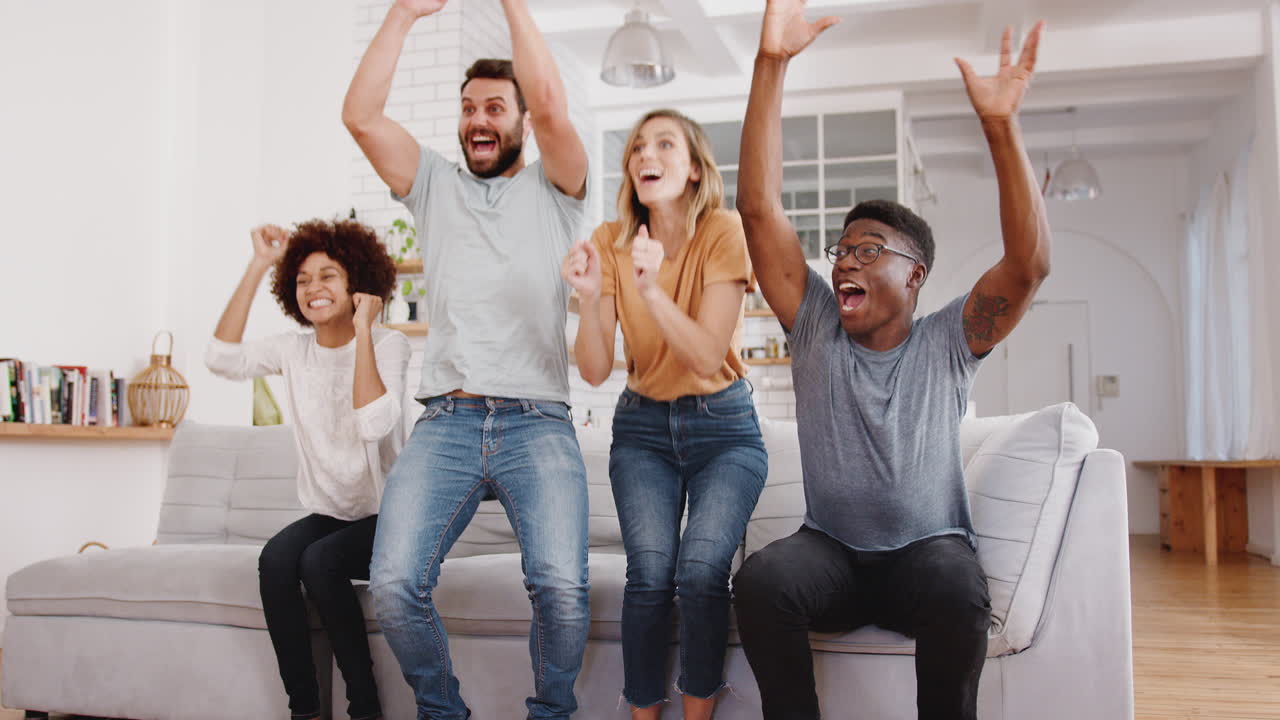 Aufgeregte Gruppe von Freunden sitzt auf dem Sofa, schaut Sport im Fernsehen und feiert