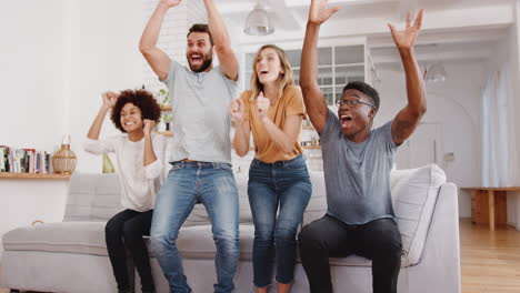 Emocionado-Grupo-De-Amigos-Sentados-En-El-Sofá-Viendo-Deportes-En-La-Televisión-Y-Celebrando