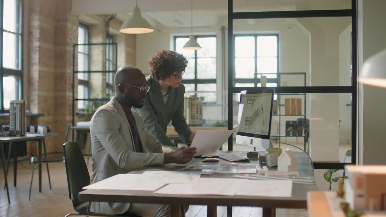 Two Architects Collaborating on Design Plans in a Modern Office