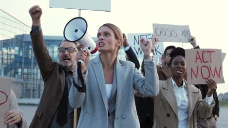 caucasian woman talking on loudspeaker with arms up in a protest with multiethnic business colleagues in the street