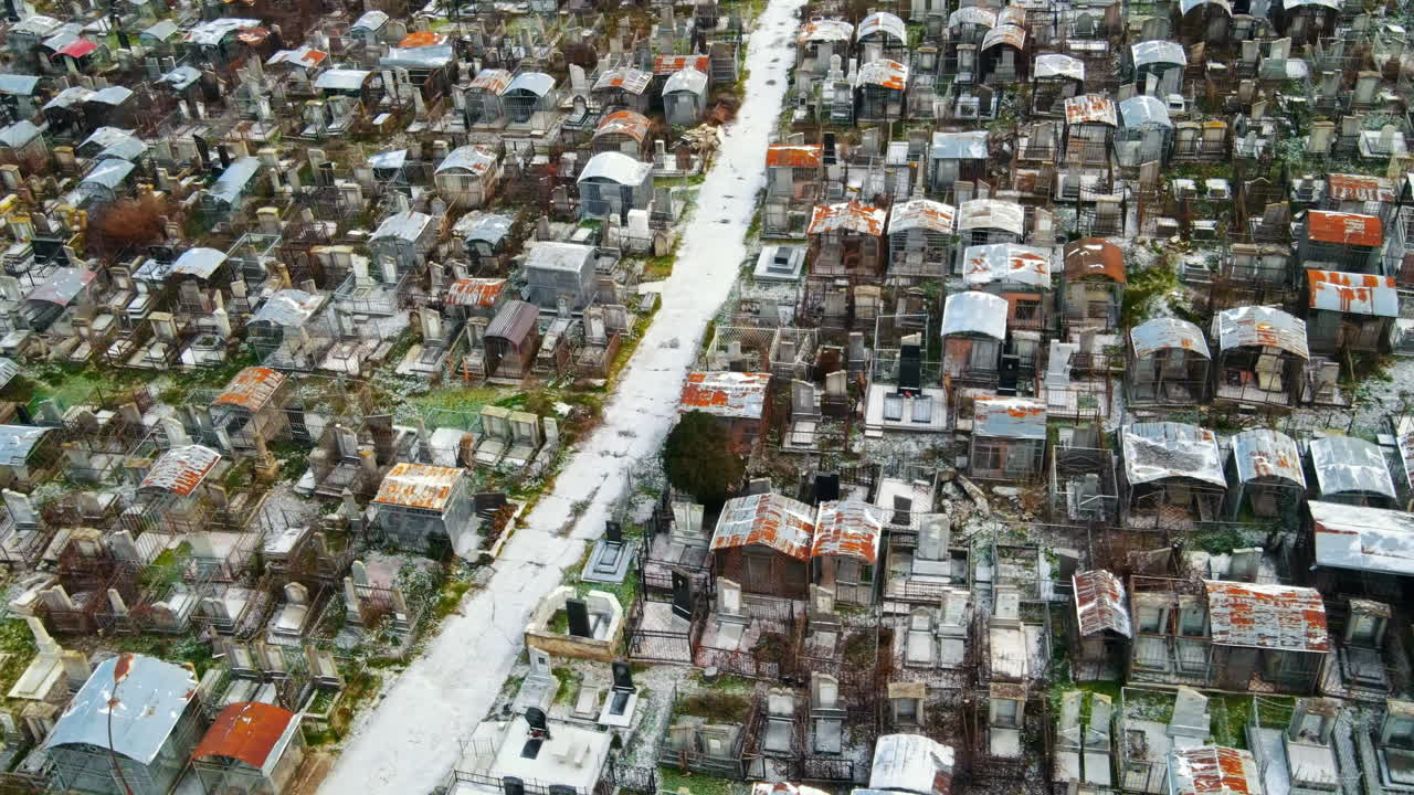 Aerial drone view of a cemetery in Chisinau, Moldova. Multiple graves, crypts, walkway, Cloudy weather, bare trees, winter