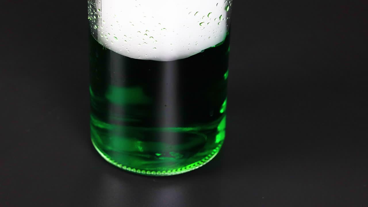 un vaso con líquido verde reacciona con hielo seco, creando efectos de burbujas y vapor en un entorno controlado