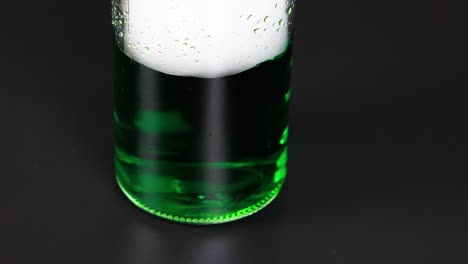 a beaker with green liquid reacts with dry ice, creating bubbling and vapor effects in a controlled environment