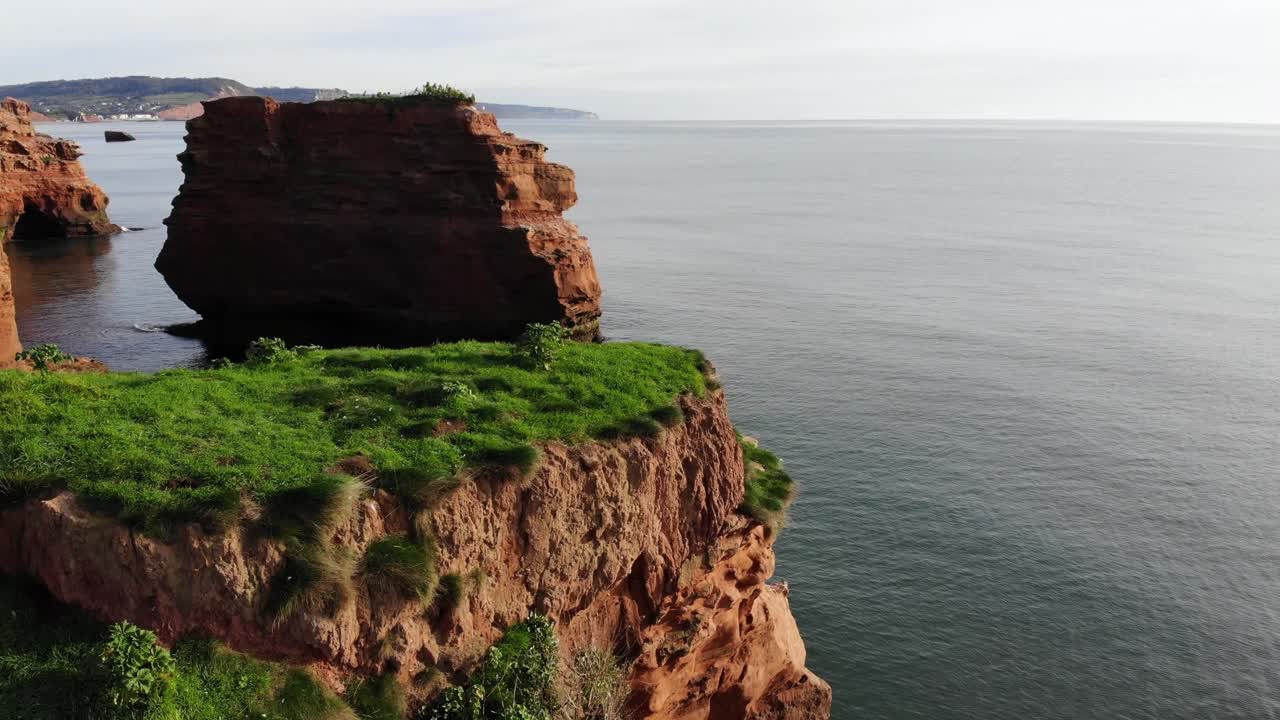 colinas cubiertas de hierba y acantilados rocosos enmarcan una vista impresionante del agua clara en la bahía de ladram