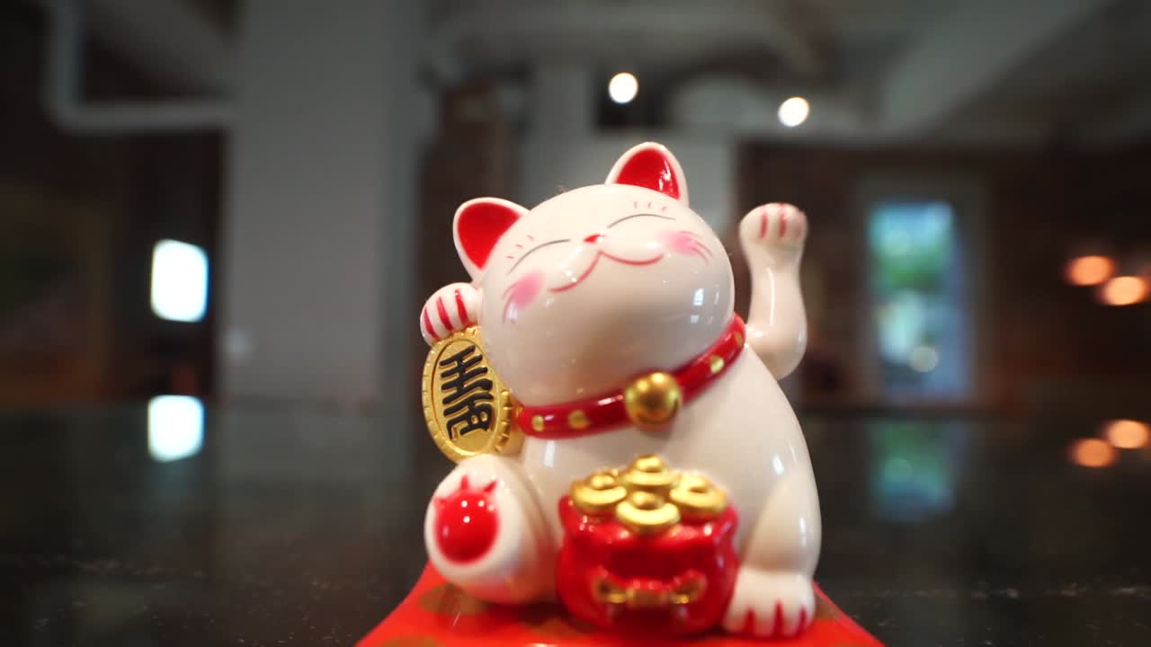 gato de la fortuna japonés que agita - maneki-neko - gato que hace señas exhibido en el frente de la tienda