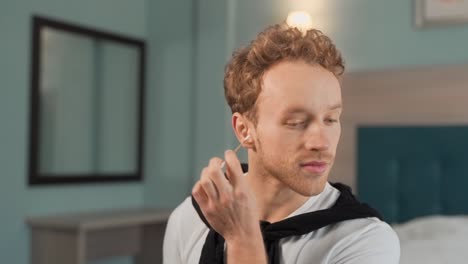 Portrait-of-a-young-man-using-ear-spray-and-a-cotton-swab-for-cleaning