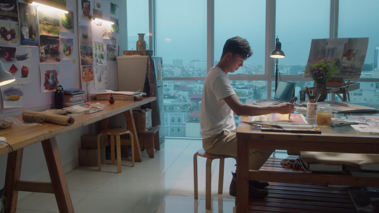 Male Artist Painting Picture at Desk in Studio