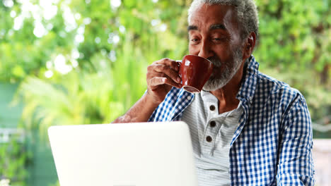 Hombre-Mayor-Usando-Una-Computadora-Portátil-Mientras-Toma-Café