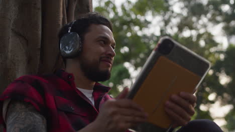 man relaxing outdoors with headphones and tablet