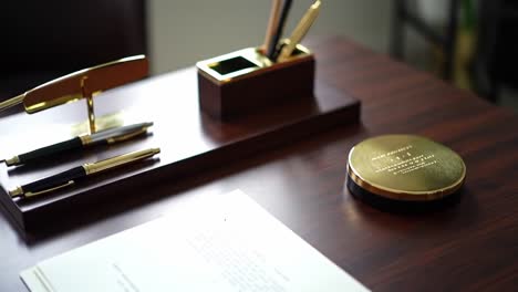 elegant desk arrangement featuring golden accents, writing instruments, and personalized coaster in a professional workspace setting