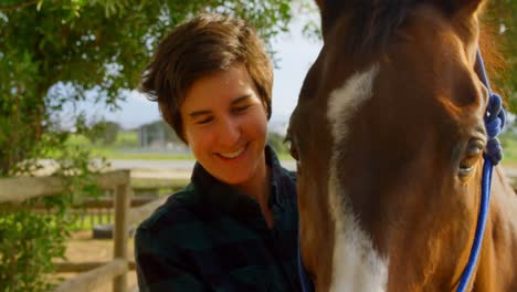 mujer de pie con un caballo en el establo 4k