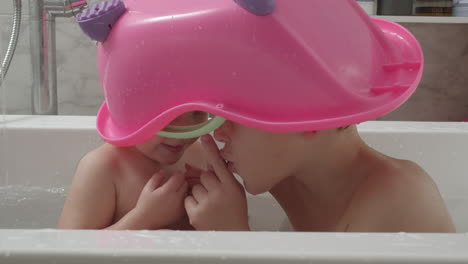 kids bathing and having fun they want to be unnoticed under toy bathtub