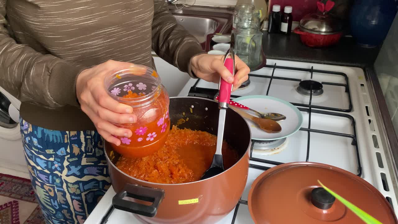 una hermosa mujer persa en iran está llenando el frasco lleno de tradicional mermelada de zanahoria en el recipiente de vidrio en la cocina en casa la cáscara de zanahoria quitado triturado con rallado cocinero comida lenta fin de semana de teherán