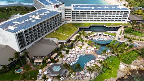 Top-down-aerial-view-of-a-resort-with-people-out-by-the-pools-near-the-turtle-bay-in-Oahu,-Hawaii