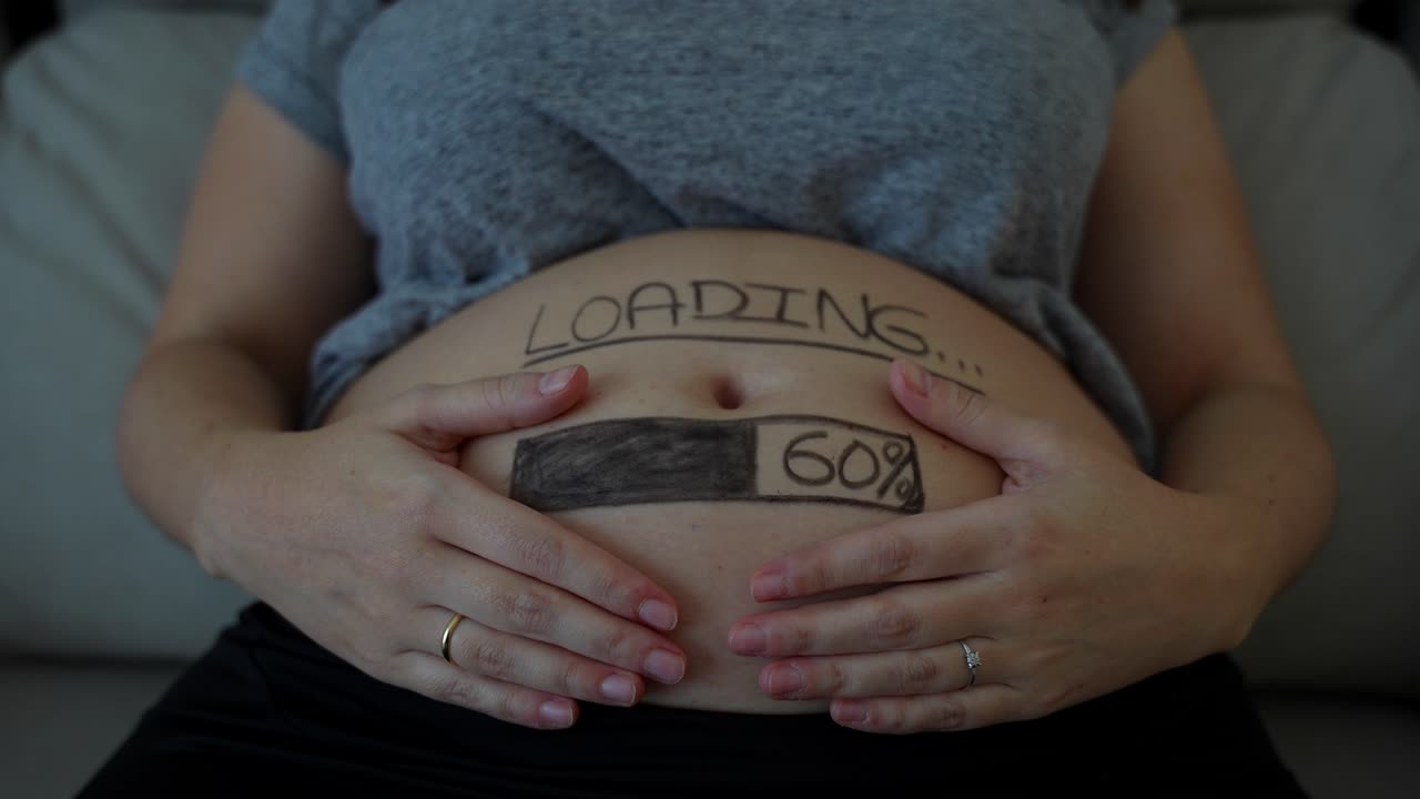 mujer embarazada mostrando su vientre con anillos de compromiso de oro y diamantes