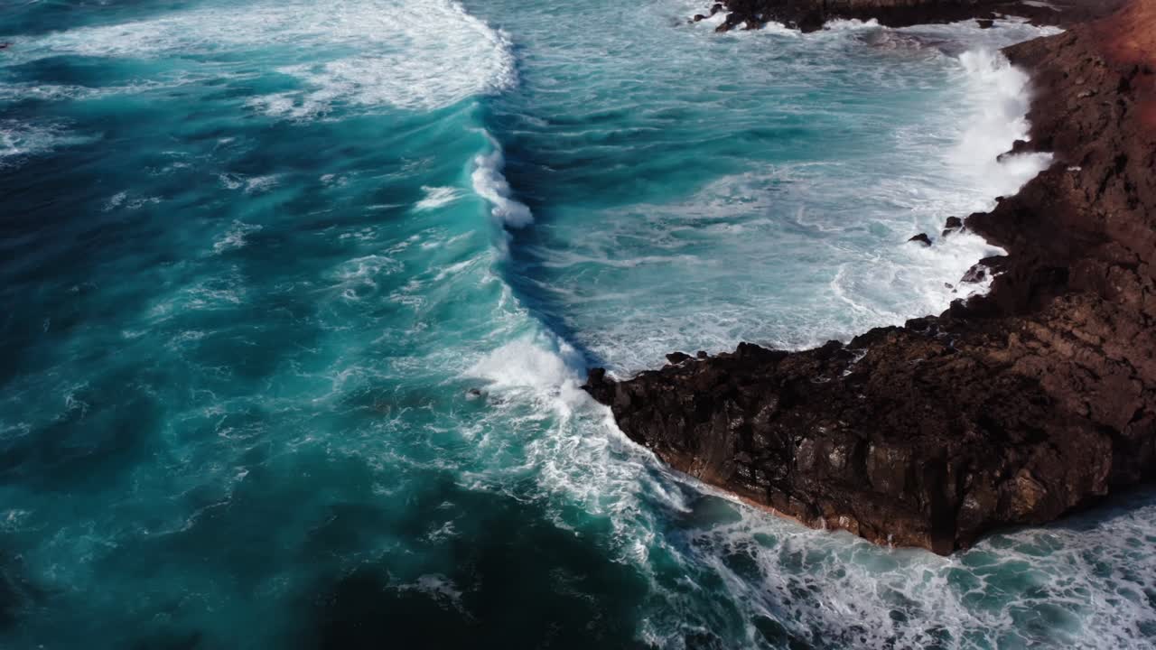Veduta aerea da drone delle onde dell'oceano che si infrangono sulle scogliere vicino a una piccola città a Lanzarote, nelle Isole Canarie