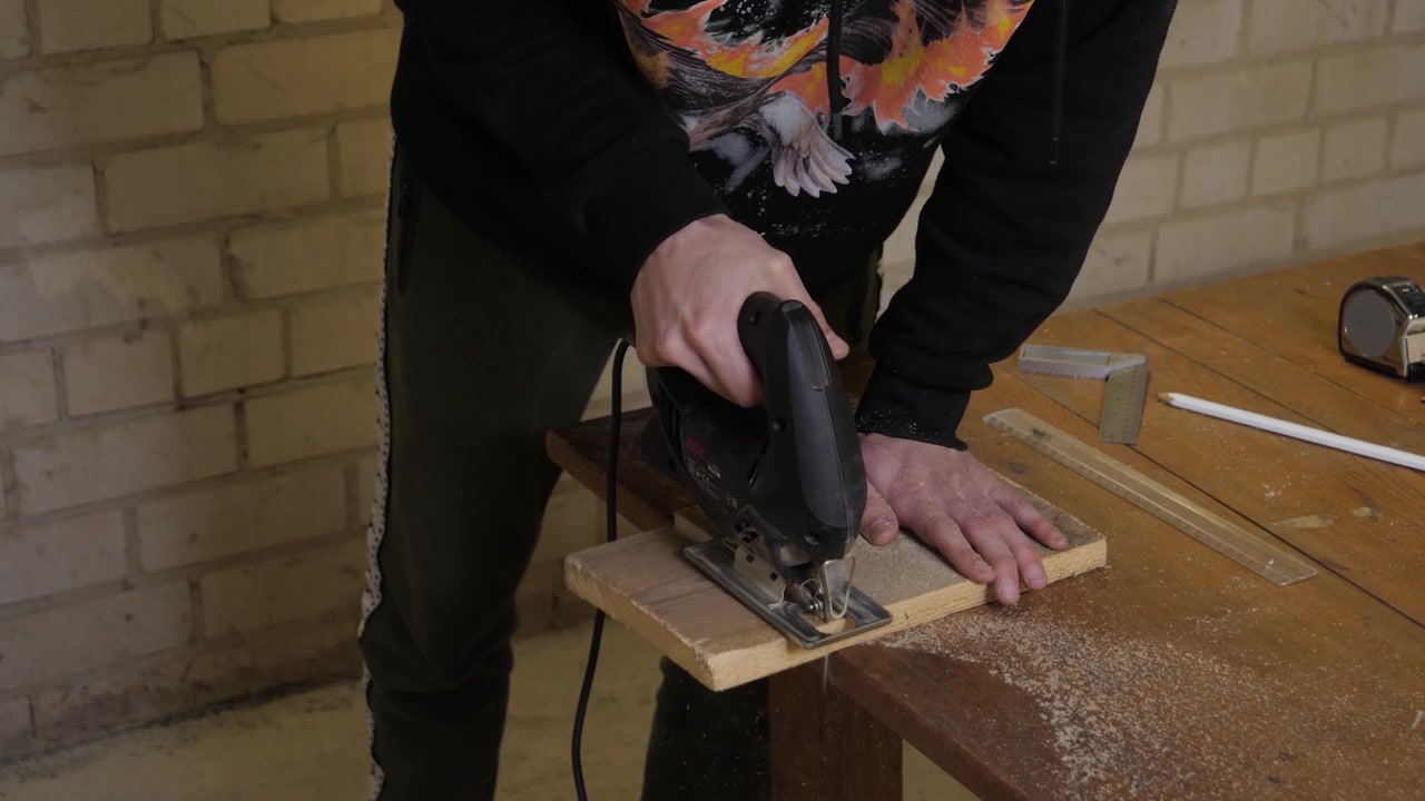 Man cut with jigsaw wood plank, static medium shot from front.