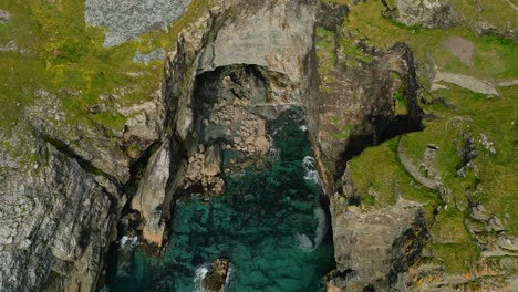 beautiful cinematic aerial shot of a cave near the ocean in the summer