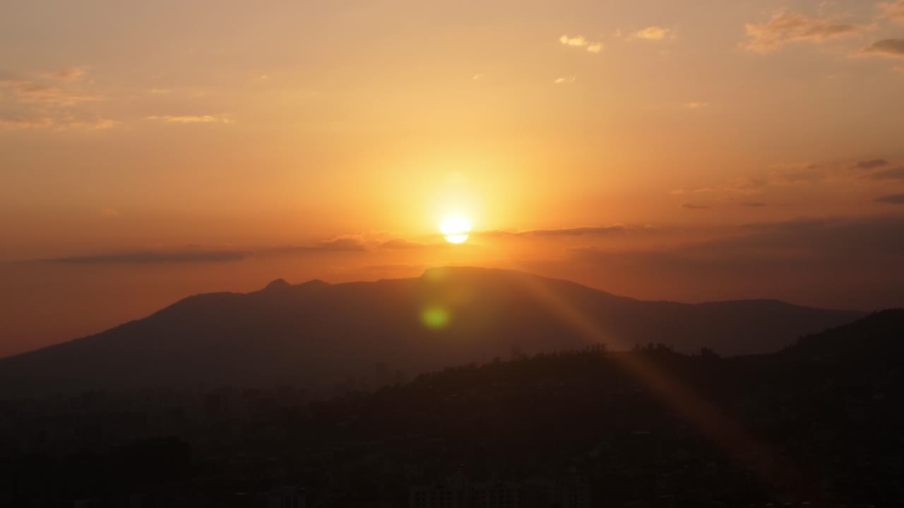 Die Sonne versinkt hinter einem Berg über der Stadt Addis Abeba, teilweise bewölkt