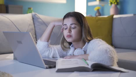 una adolescente somnolienta y agotada mirando su computadora portátil.